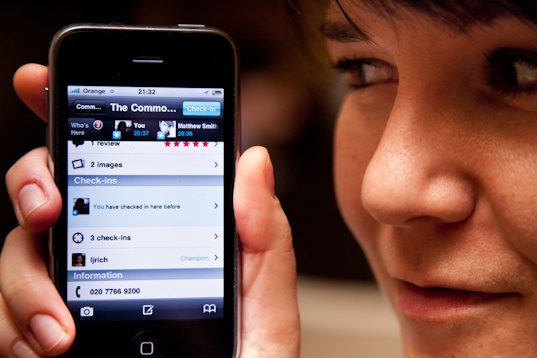Lea checking in to a restaurant on her iPhone at a preview dinner, London