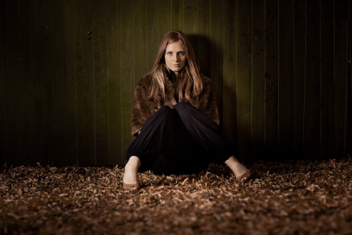 Girl among leaves in a spotlight, the photographer's best photo assistant