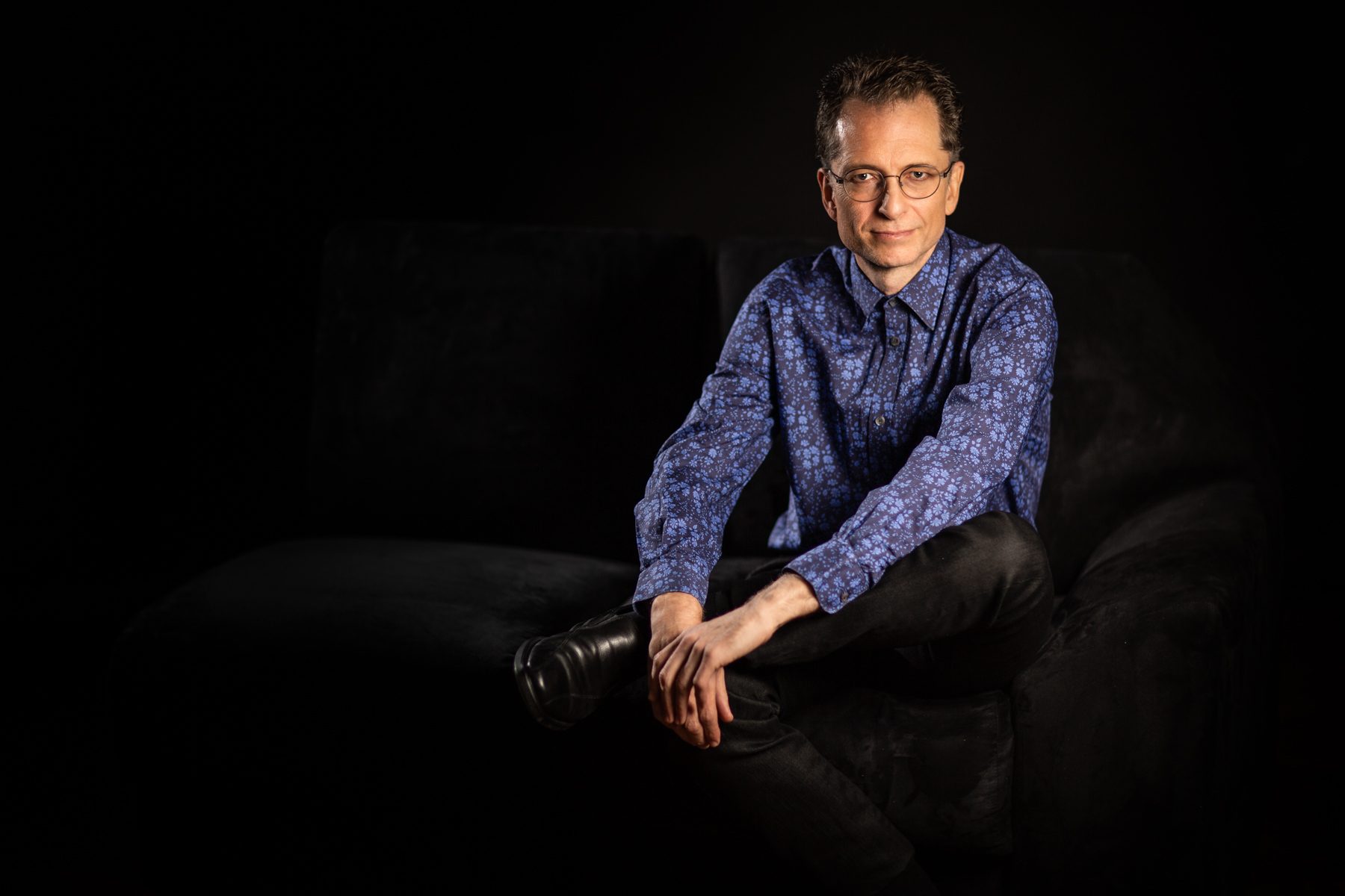 Gavin Greenaway, composer, conductor and pianist, on a sofa, portrait by Mat Smith Photography, Air Studios, Hampstead