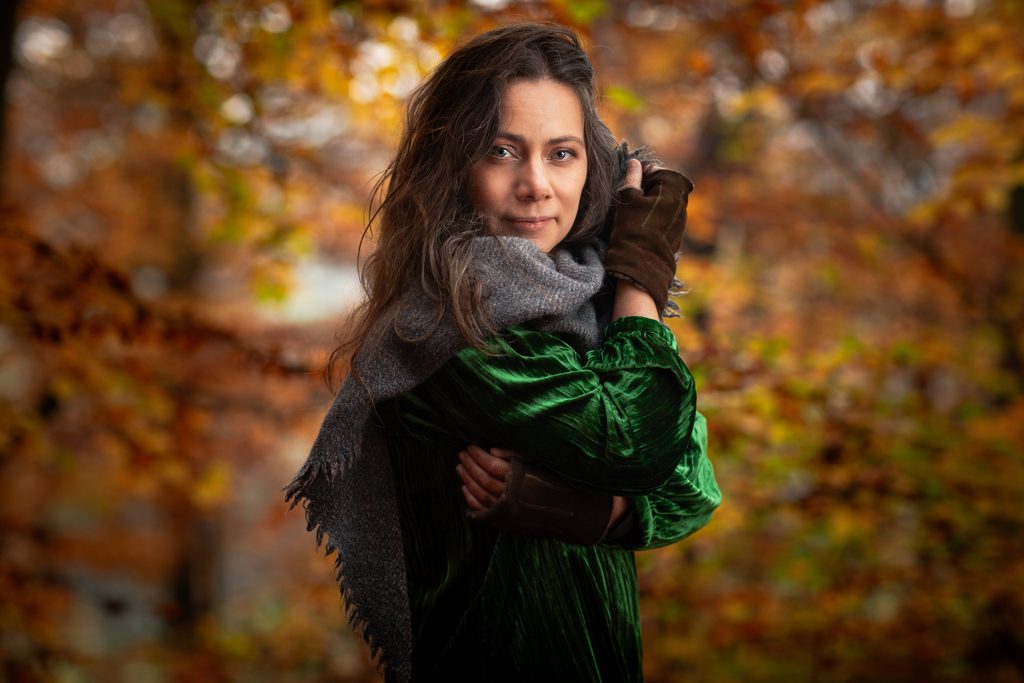 Rebecca Knight, cellist, in a green velvet dress and grey scarf against autumn beech leaves, portrait by Mat Smith Photography, Beaconsfield