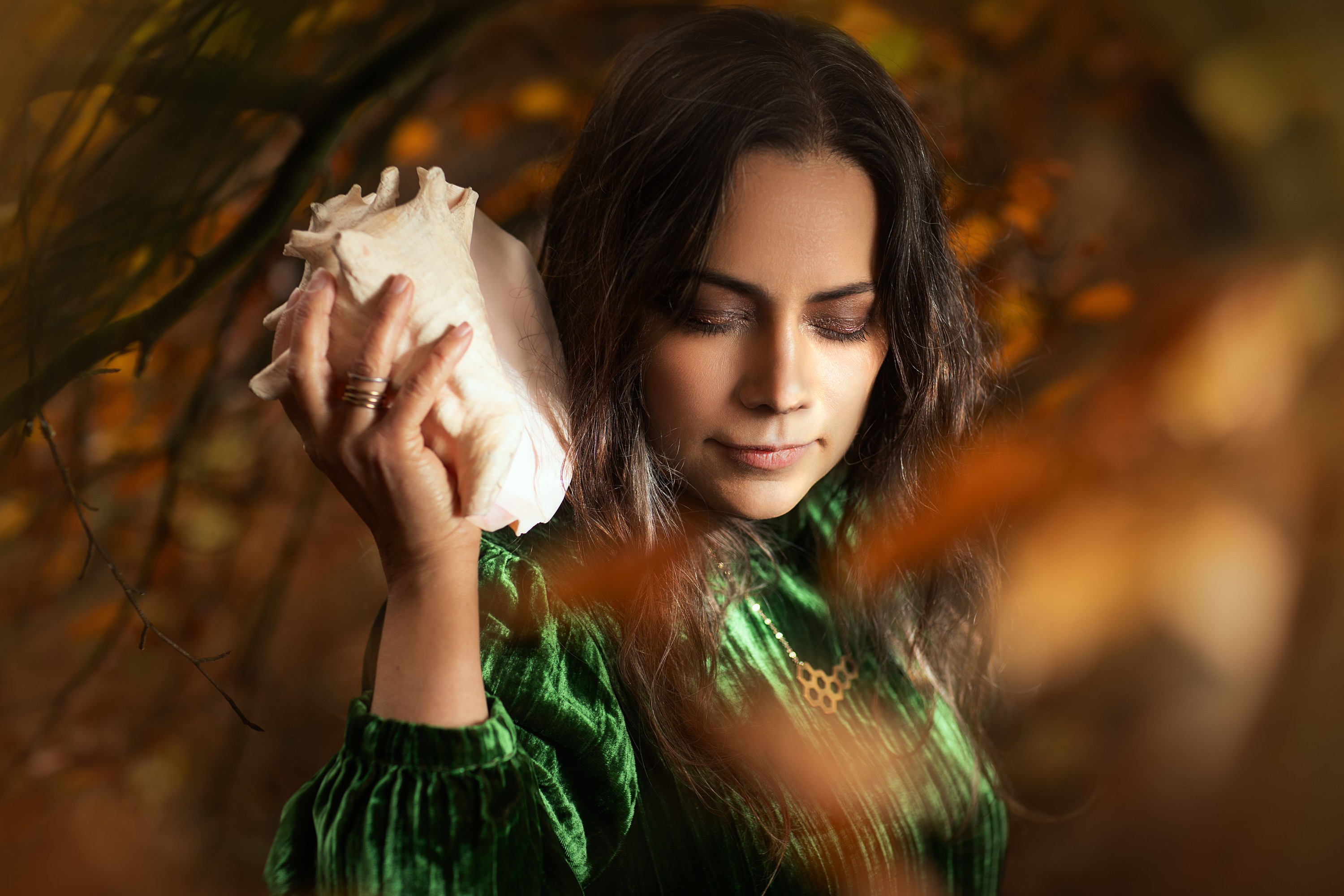 Rebecca Knight, cellist, eyes closed, holding a conch shell to her ear among autumn beech leaves, portrait by Mat Smith Photography, Beaconsfield