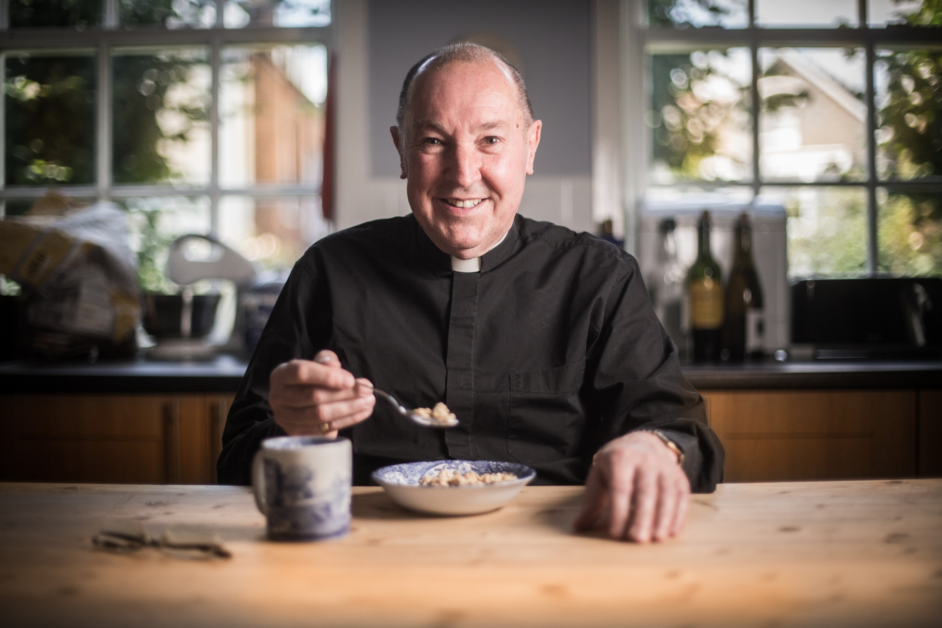 Revd Guy Pope, London vicar, at breakfast with a bowl of cereal, portrait by Mat Smith Photography