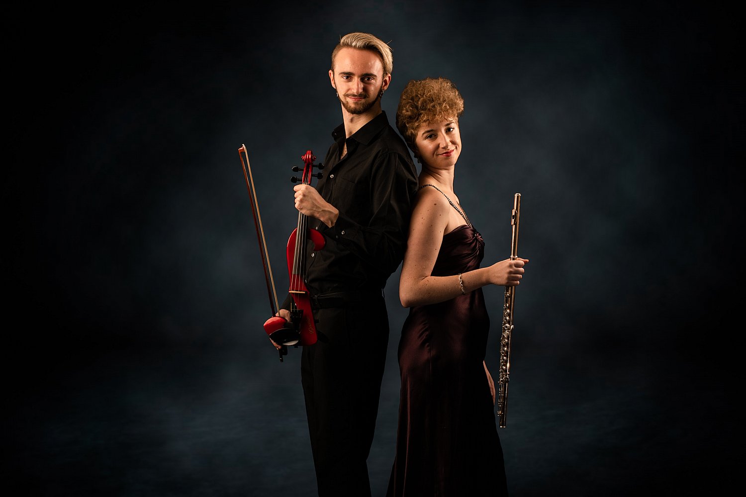 Violin and flute duo back to back against a stormy backdrop